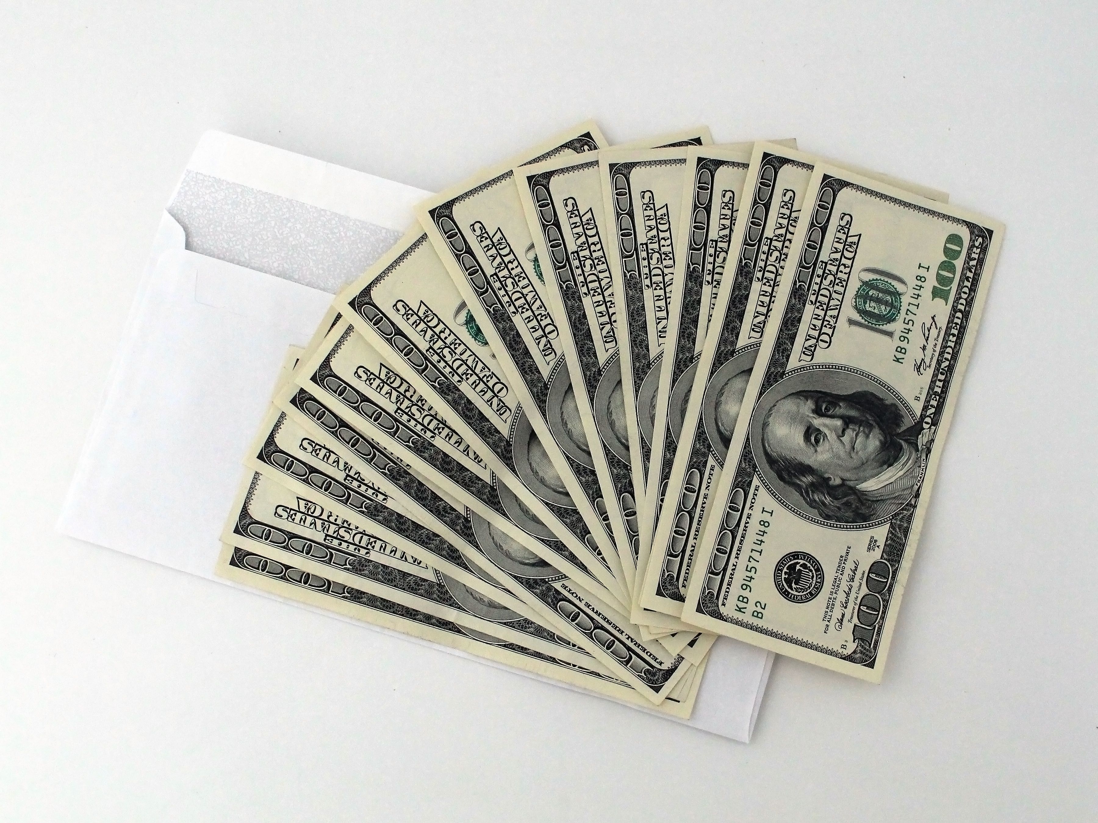 US hundred-dollar bills fanned out from a white envelope, illustrating a lawsuit cash payout