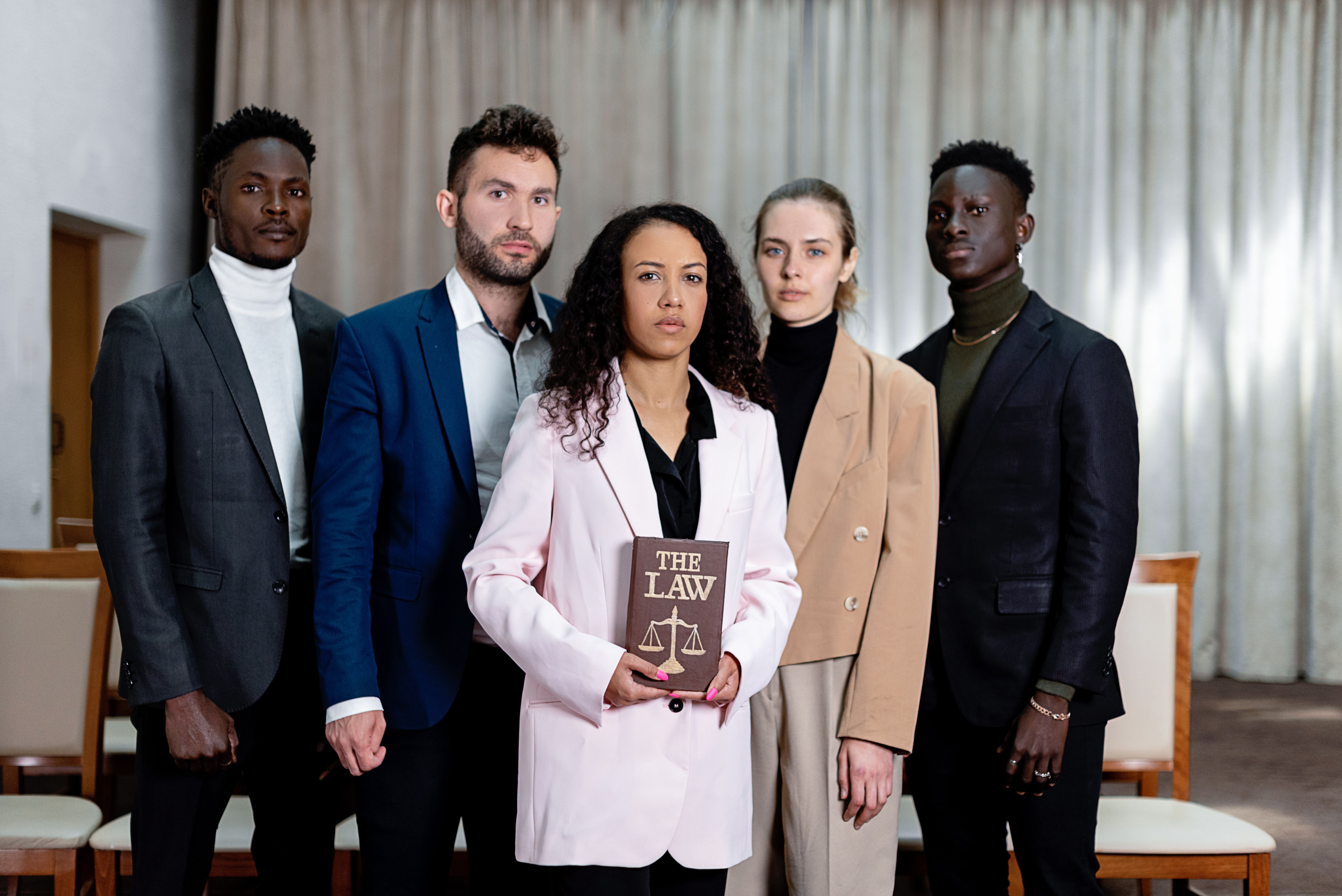 Diverse group of corporate lawyers posing confidently with a law book in an office
