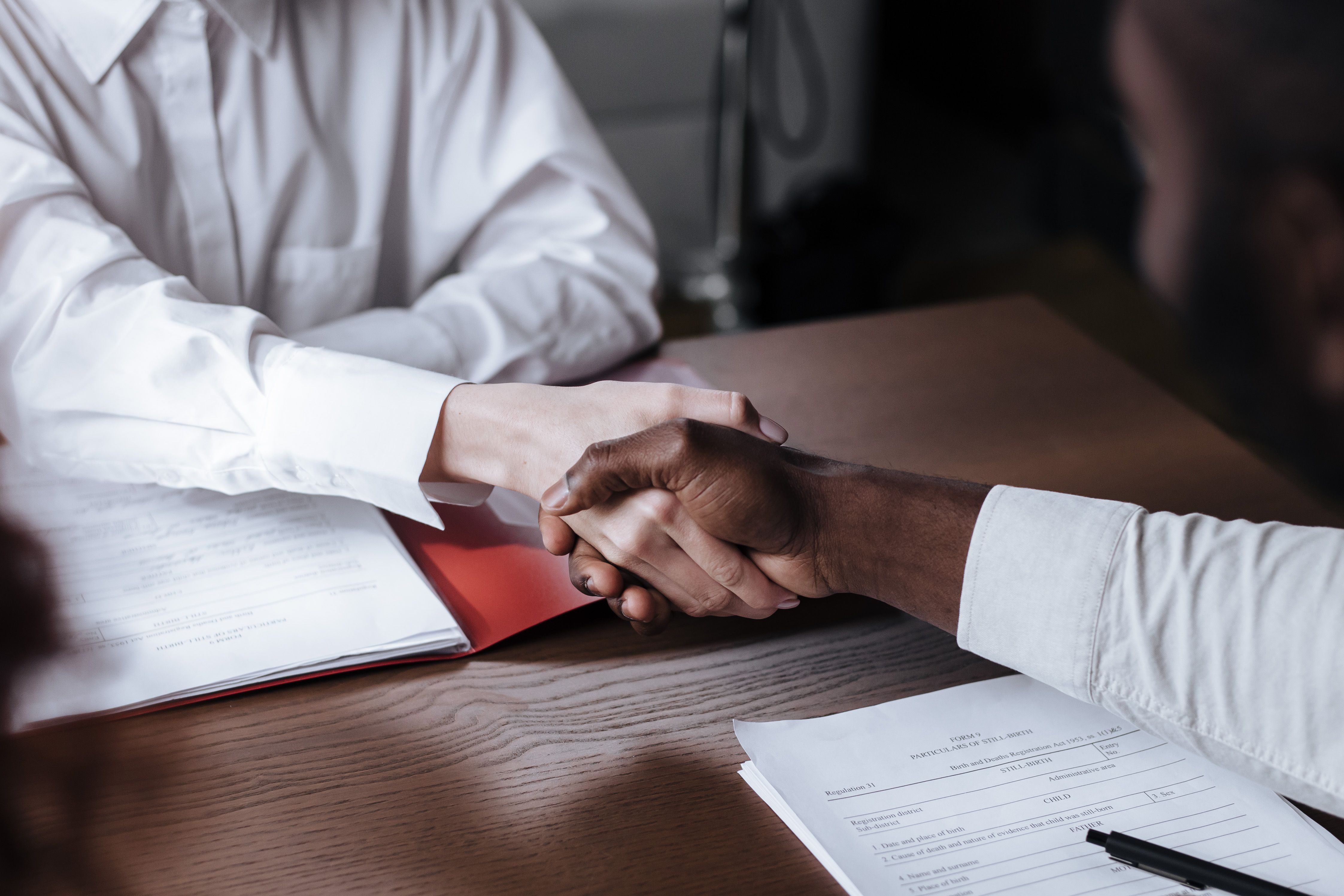 Business handshake over legal documents sealing a corporate lawsuit settlement agreement