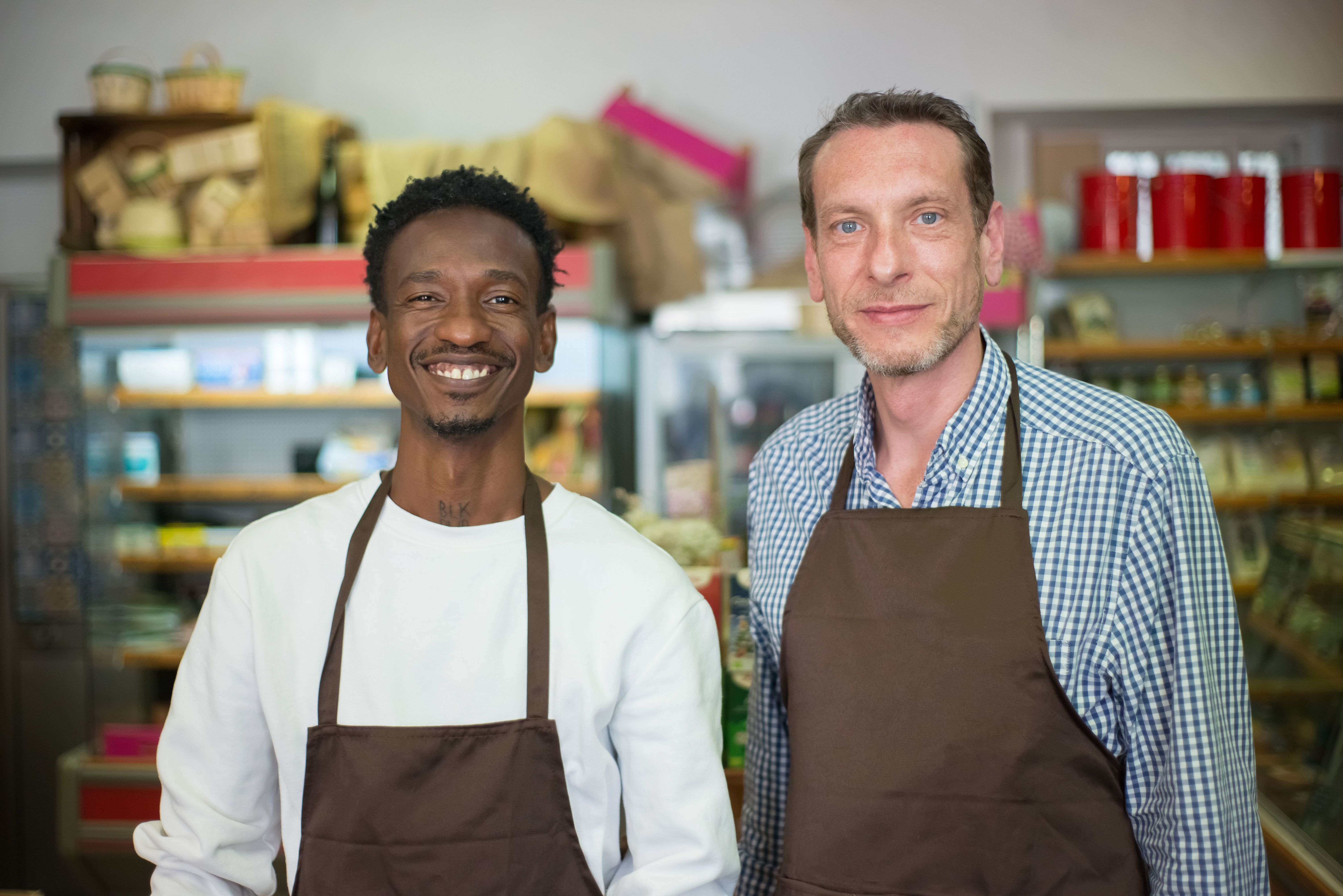 Two happy small business store owners smiling in their local grocery store