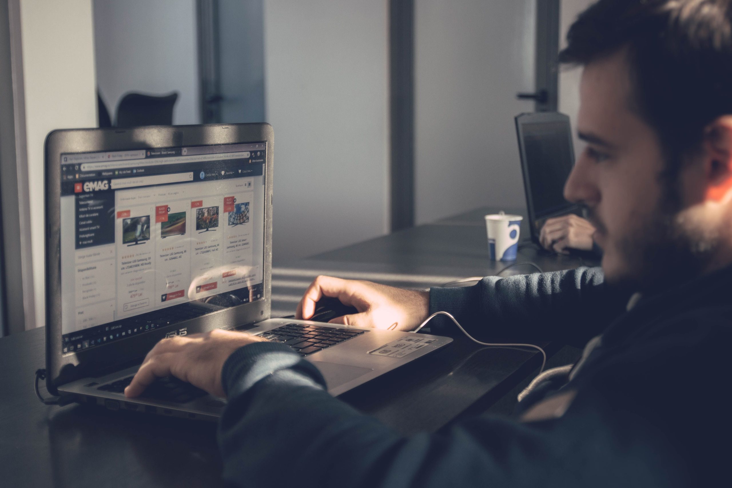 Small business owner using a laptop to browse an online marketplace in a modern office