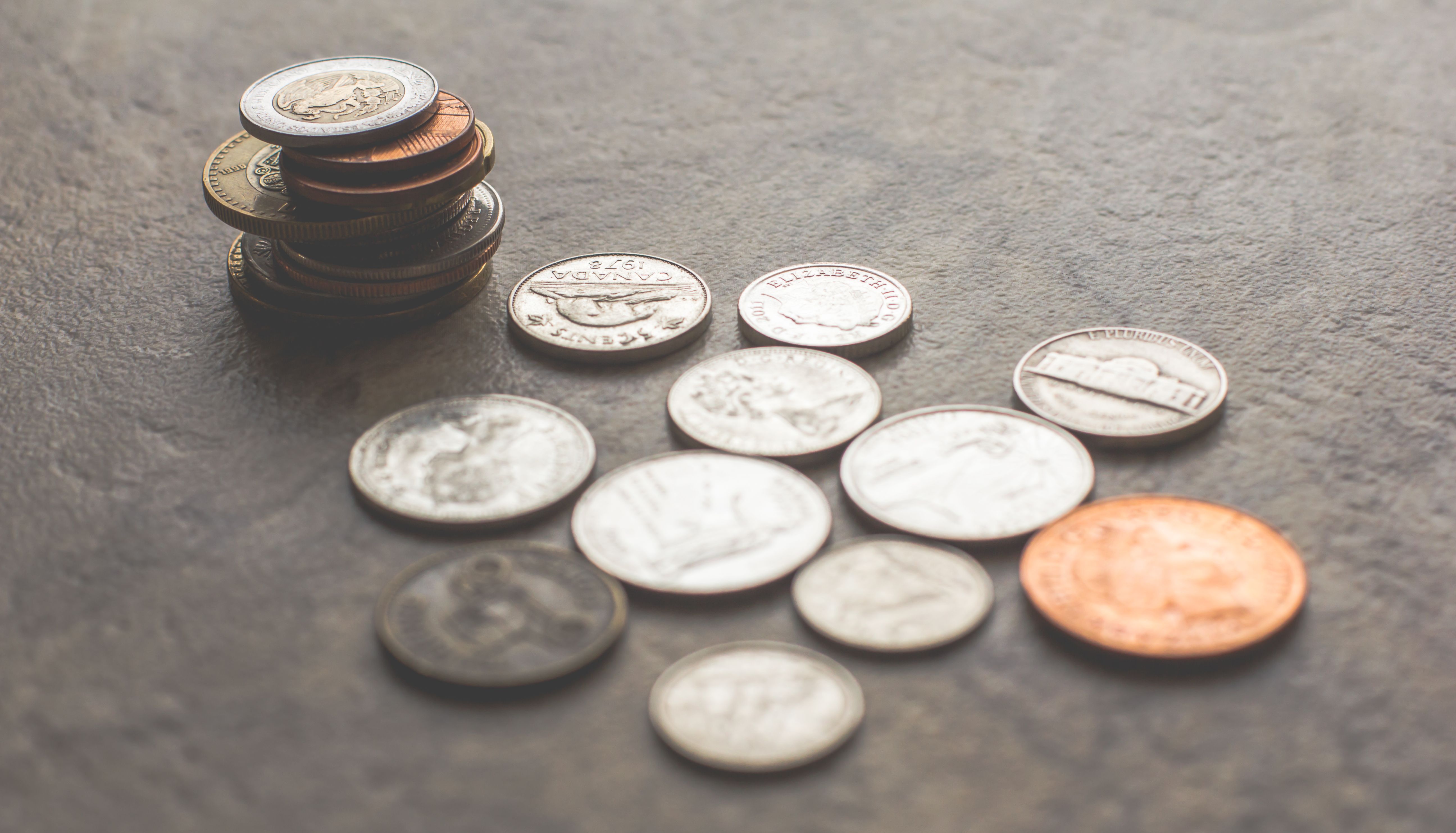 Assorted coins stacked and scattered on a textured surface, representing funding capital