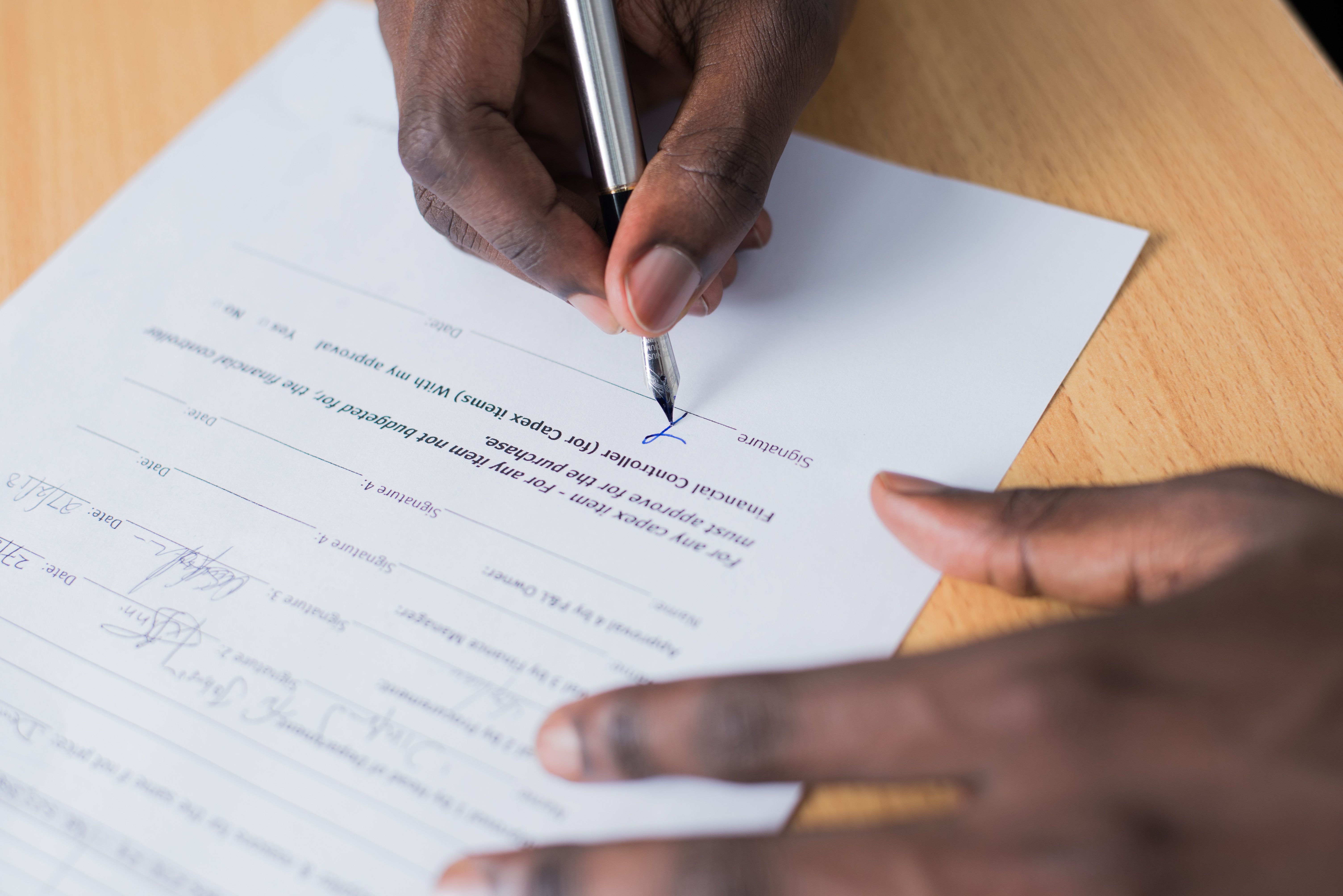 Close-up of a person's hand signing a business contract with a pen