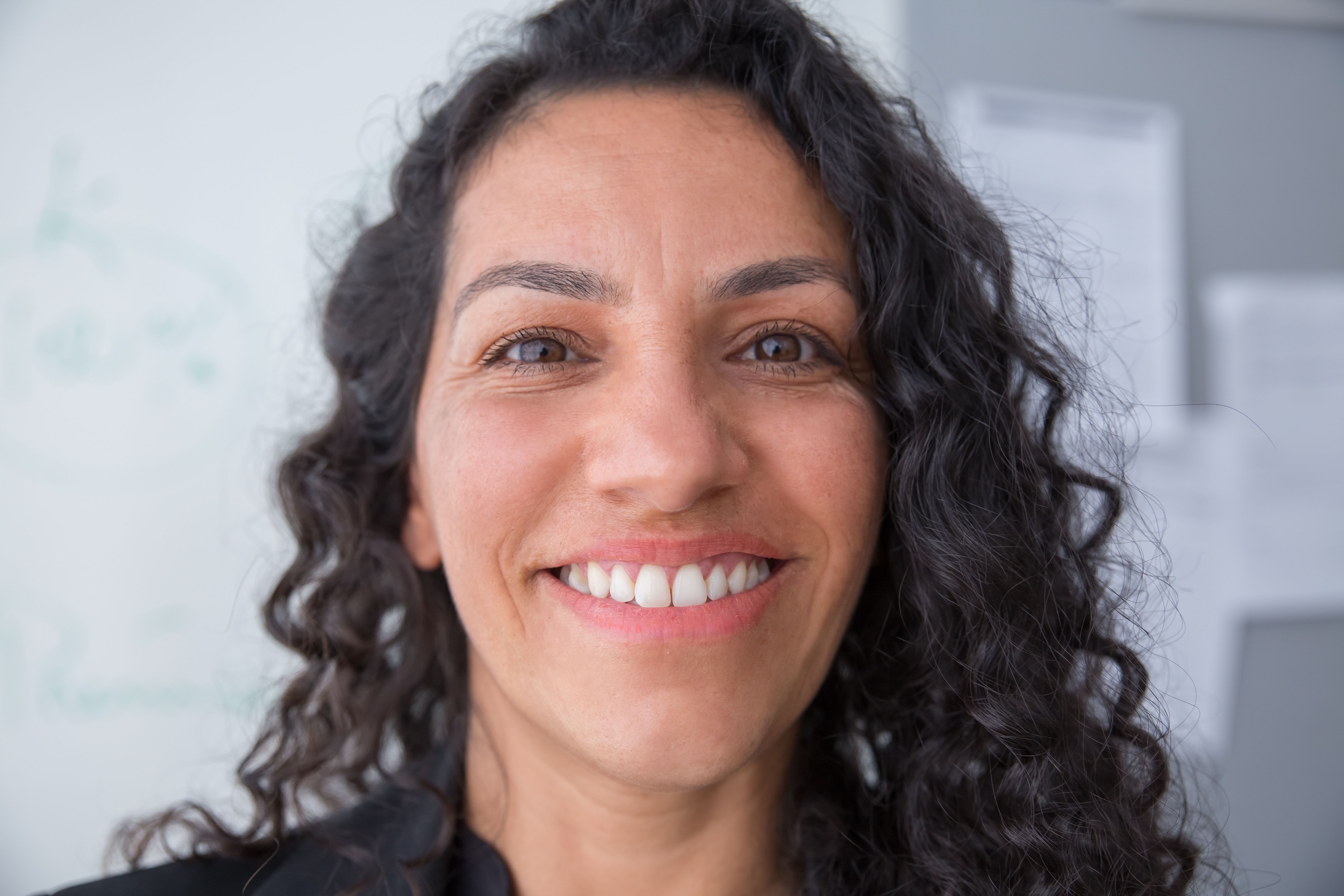 Close-up portrait of a woman smiling warmly with a confident, approachable expression.