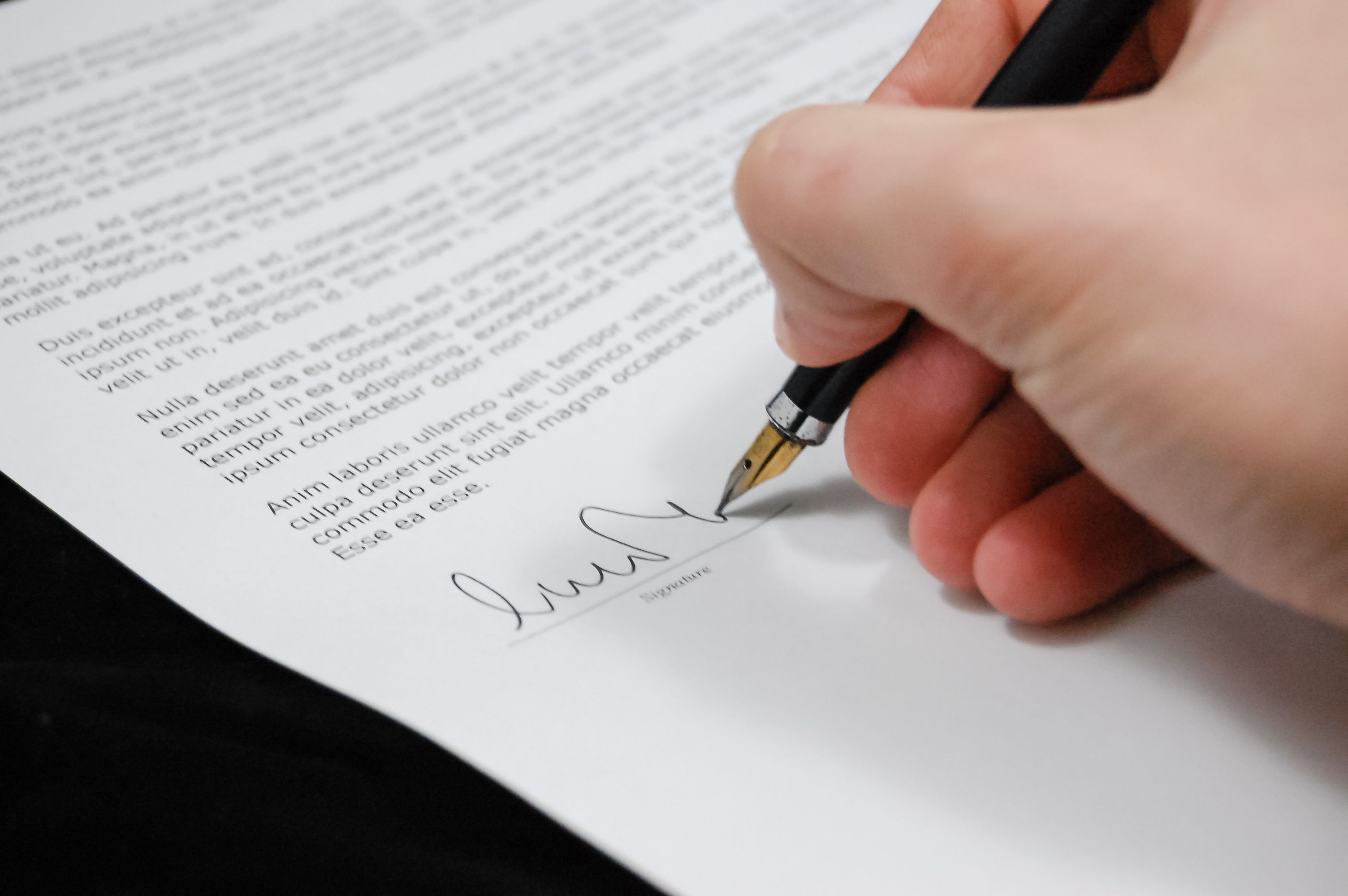 Hand signing a legal agreement with a fountain pen, illustrating a litigation funding contract.